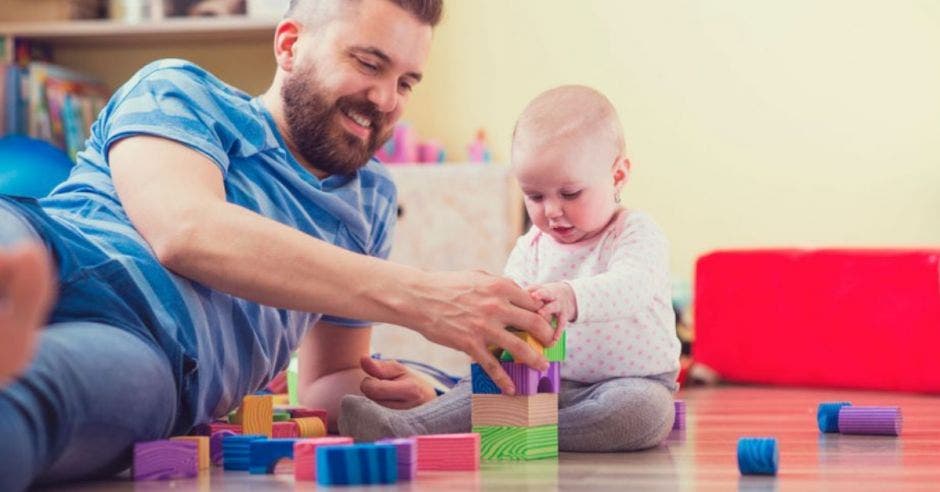 papá jugando con bebé en el piso