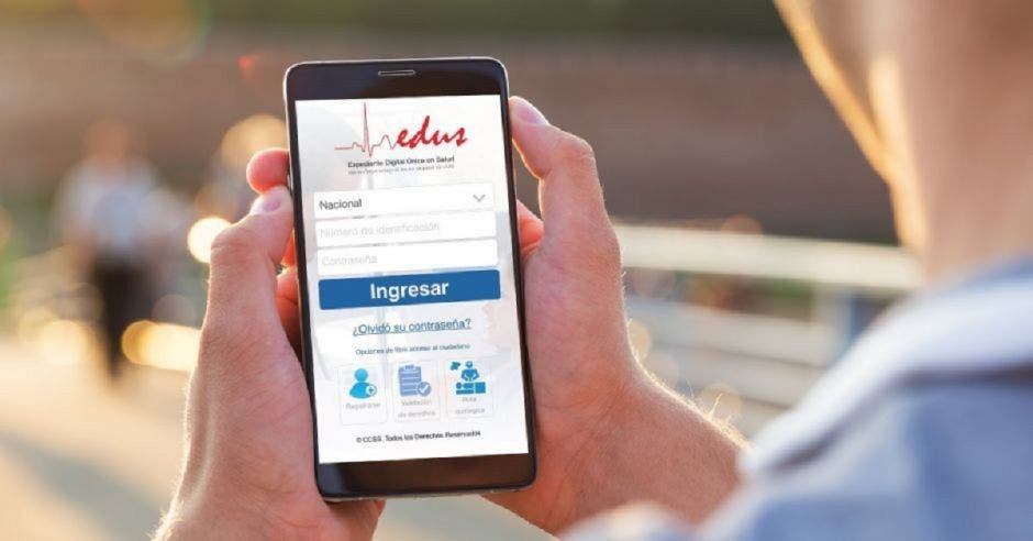 Una persona sosteniendo un celular en sus manos con el app del EDUS