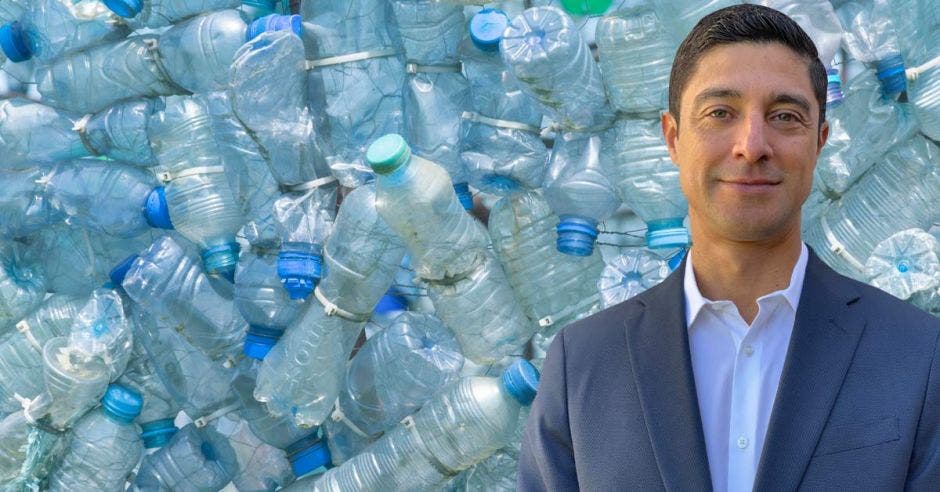 un hombre con saco sobre un fondo de botellas de plástico