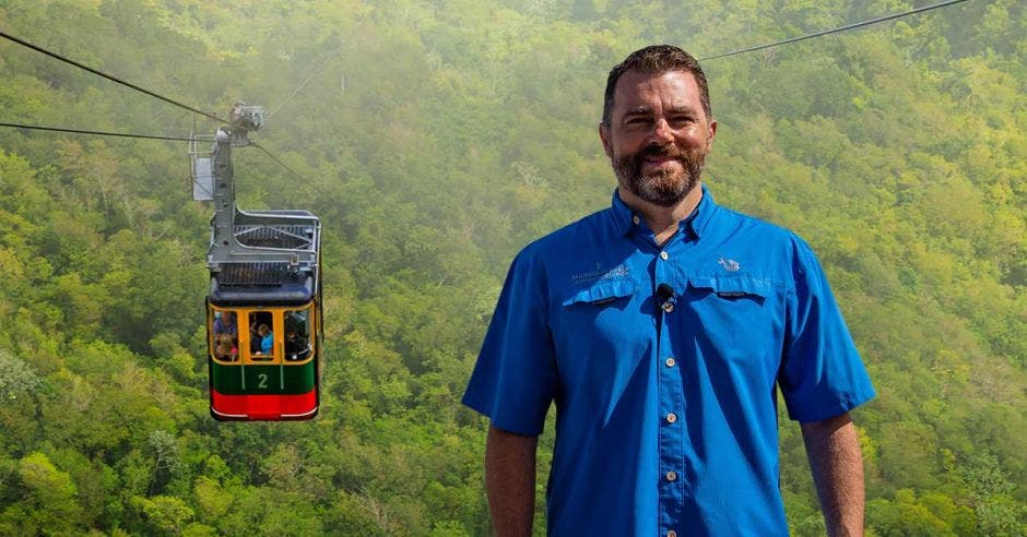 un hombre de camisa azul sobre el fondo de un teleférico en la naturaleza