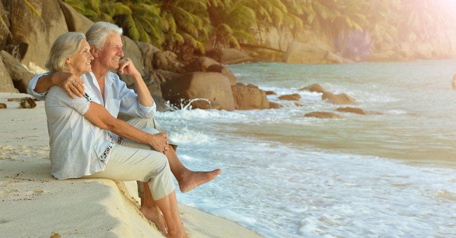 una pareja de adultos mayores disfruta de la vista en el mar