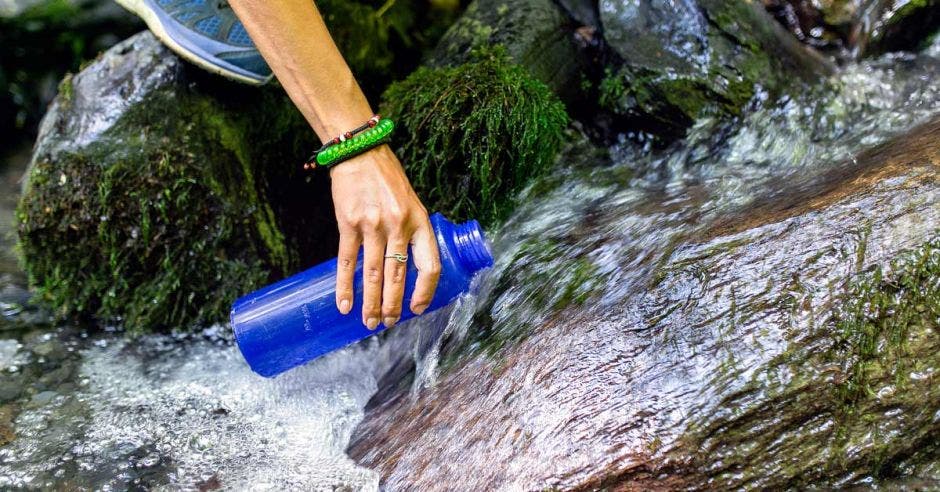 una mujer recoge agua de un riachuelo