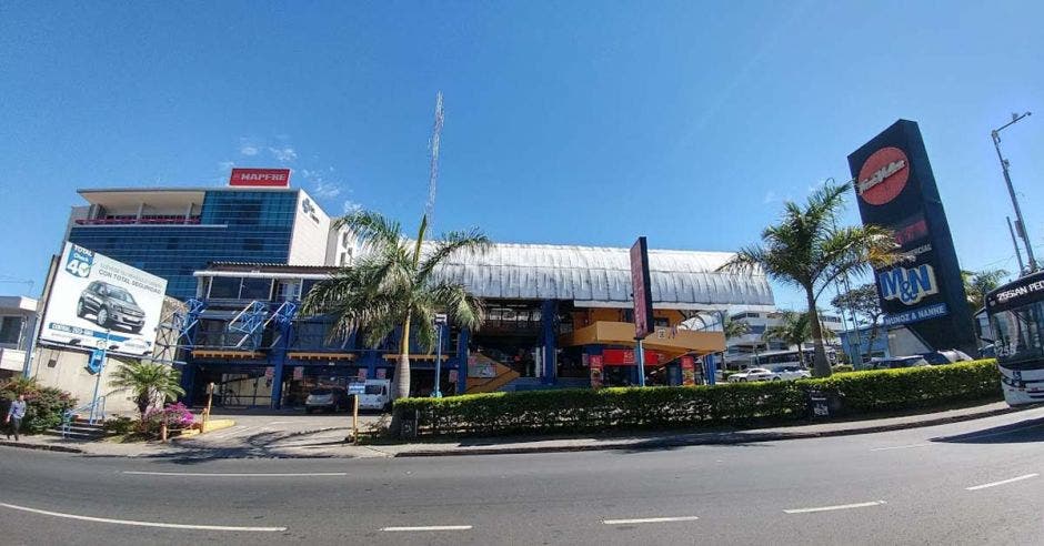 un supermercado amplio con palmeras y arbustos en la entrada