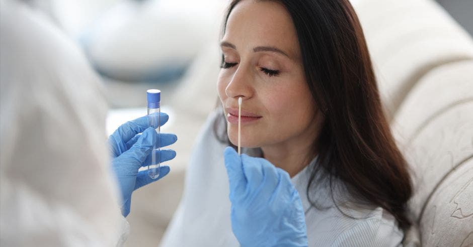 El asistente de laboratorio médico con traje protector se toma la toallita de la nariz de un paciente enfermo en casa. Pruebas de laboratorio para el concepto de coronavirus