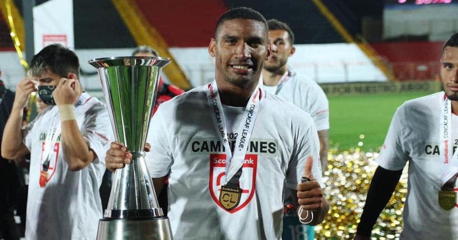 un hombre de camisa blanca sostiene un trofeo de metal