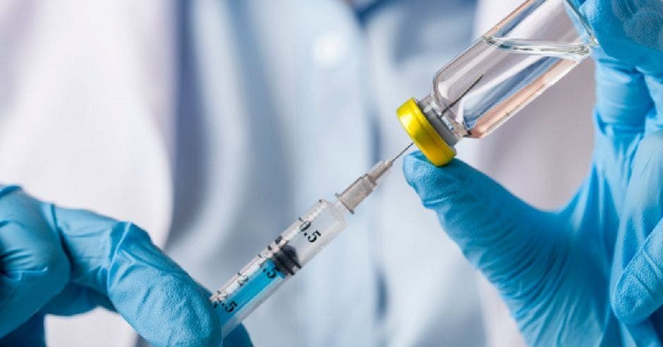un doctor extrae líquido de una vacuna a través de una jeringa