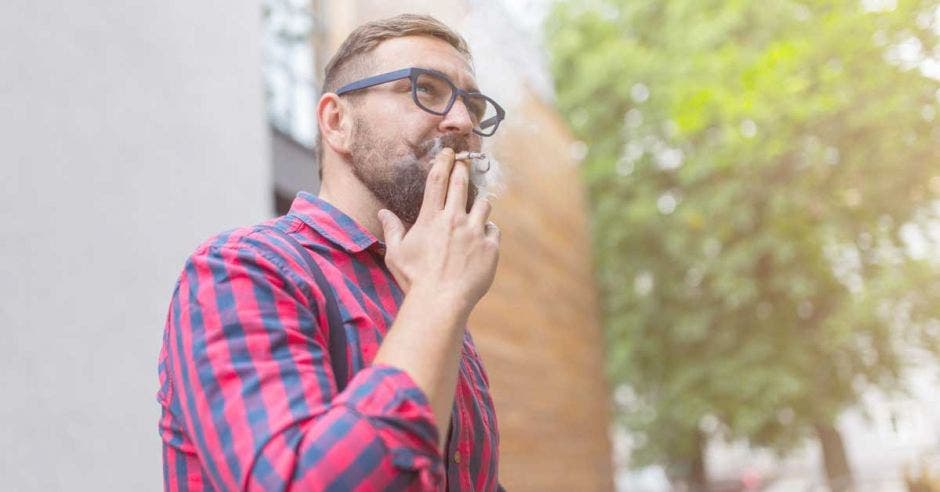 un hombre fuma un cigarrillo de marihuana a las afueras de un edificio