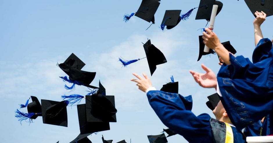 Estudiantes lanzando los birretes al aire