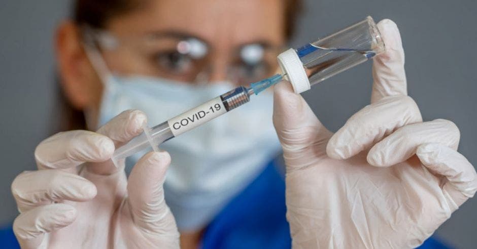 médico sosteniendo vacuna covid-19