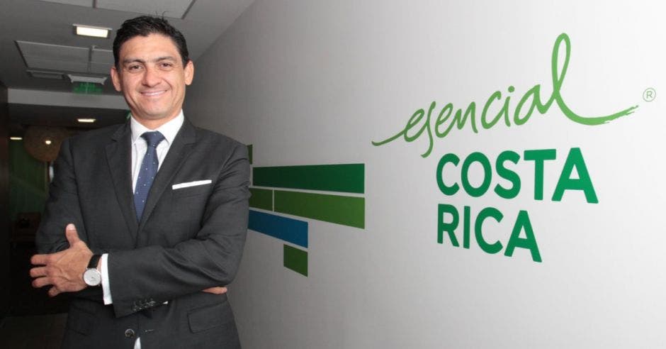 Hombre de traje a la par de pared que dice esencial costa rica