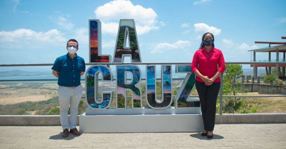 dos personas junto a un letrero que dice La Cruz