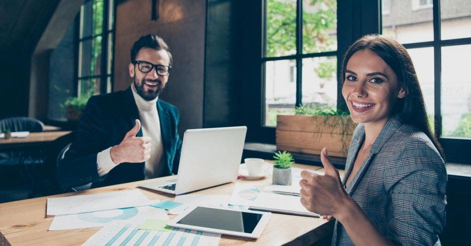 hombre y mujer trabajando y sonriendo con el pulgar levantado