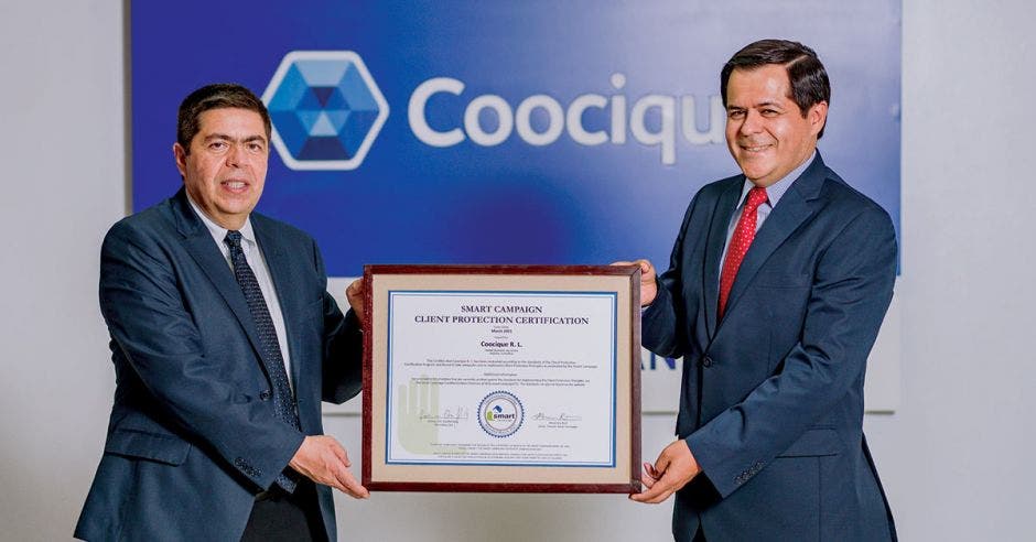 dos hombres de saco y corbata sostienen una certificación de vidrio