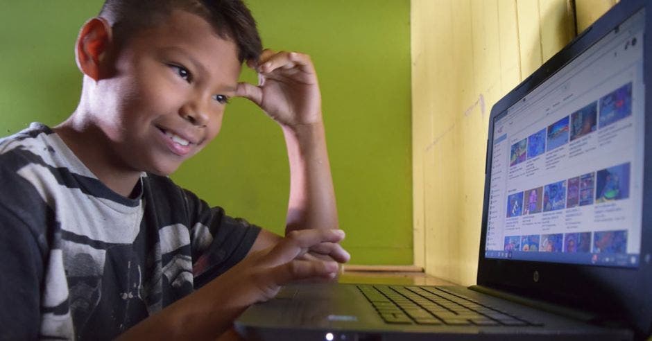 Niño sonriendo frente a una computadora