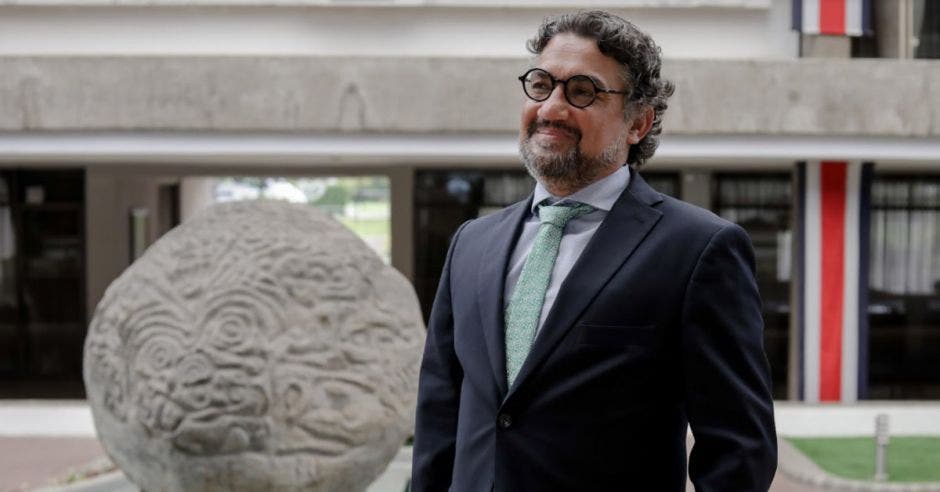 un hombre de anteojos sonriente sobre un fondo de una jirafa