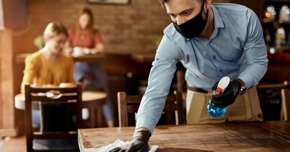 un mesero limpia una mesa de madera