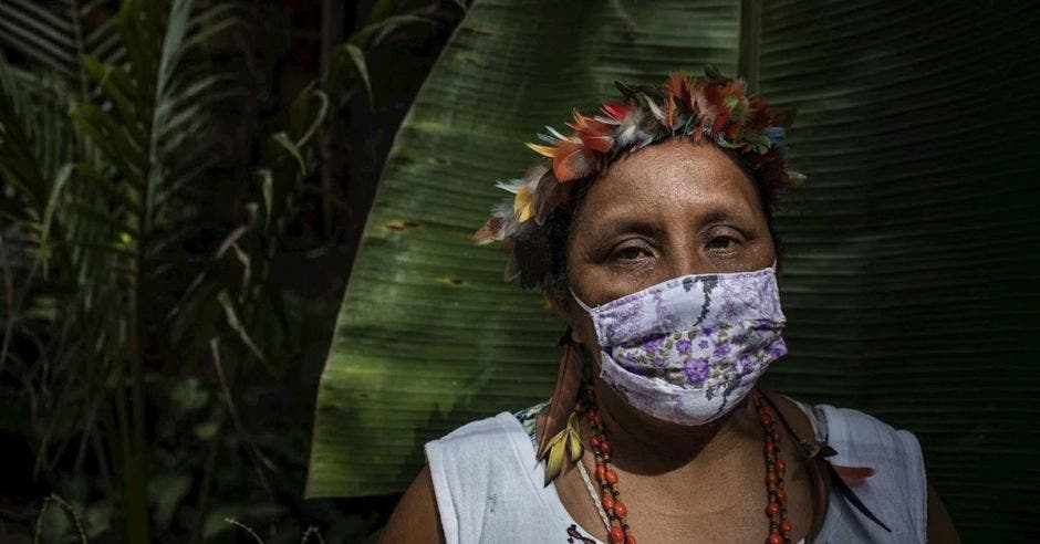 Mujer con mascarilla puesta y planta detrás