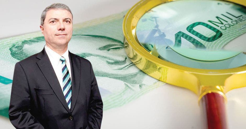 Gerardo Corrales frente a lupa sobre billete de 10 mil colones