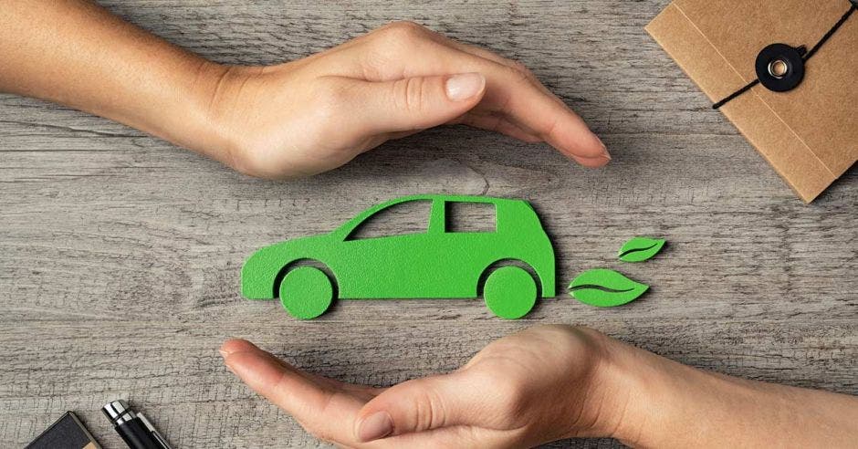 figura verde de automóvil entre manos en postura curva