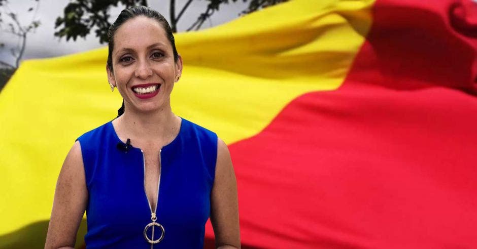 Carolina Hidalgo, precandidata del PAC en primer plano. En segundo plano una bandera del PAC de color rojo y amarillo