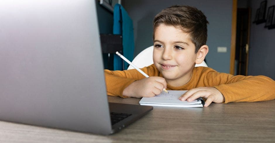 Niño frente a computadora con bolígrafo