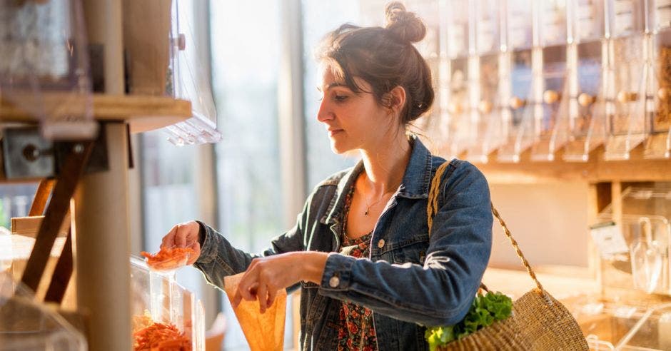 joven comprando en una tienda de comida a granel. Ella compra pasta orgánica