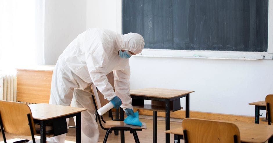 Una persona limpiando y sanitizando un aula