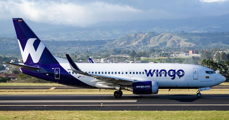 un avión blanco con vetas violeta estacionado en una pista de aterrizaje