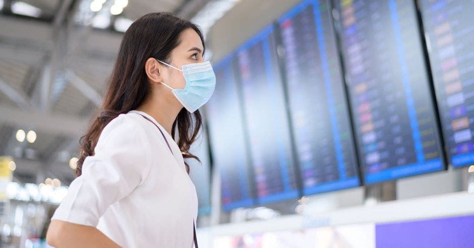 una mujer con mascarilla a punto de abordar un avión