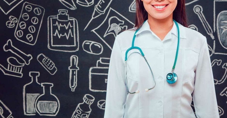 Una mujer con uniforme de medicina y al fondo dibujos de medicina