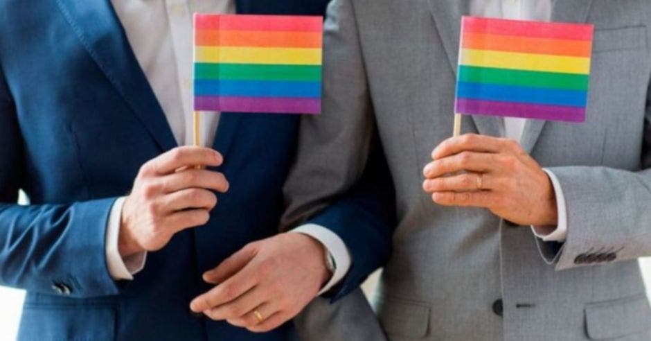 Un par de hombres casándose sostienen una bandera diversa