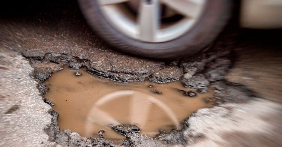 un gran hueco en la carretera lleno de agua sucia