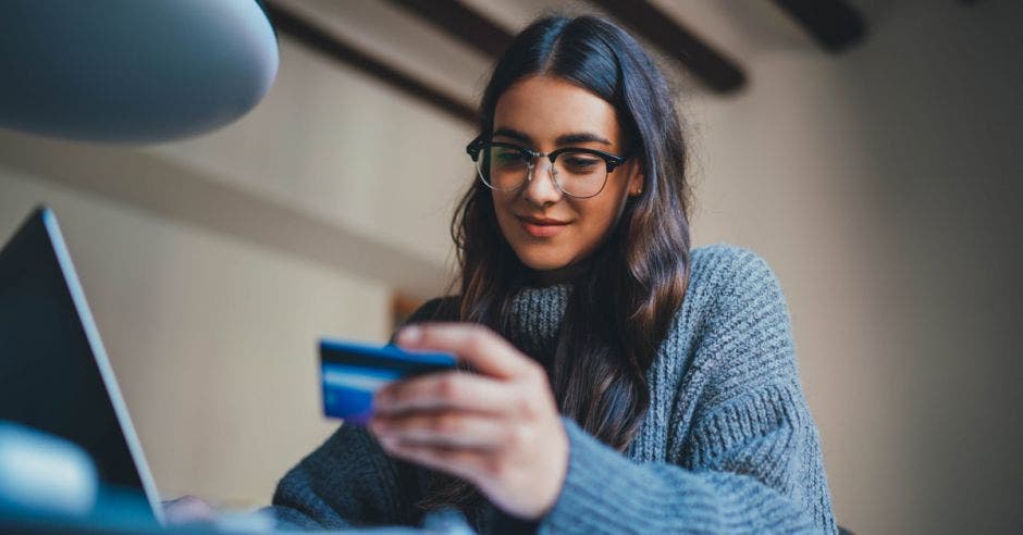 Joven hermosa mujer trabajando en casa con tarjeta de crédito y usando computadora portátil