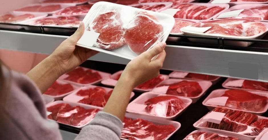 una mujer escoge cortes de carne en un supermercado
