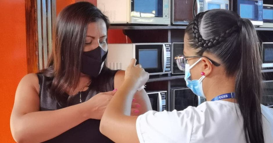 mujer docente de cabello castaño y blusa café recibiendo vacuna contra la Covid-19 Covid-19