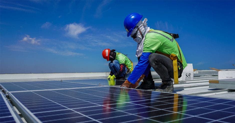 dos hombres sobre un techo instalando paneles solares