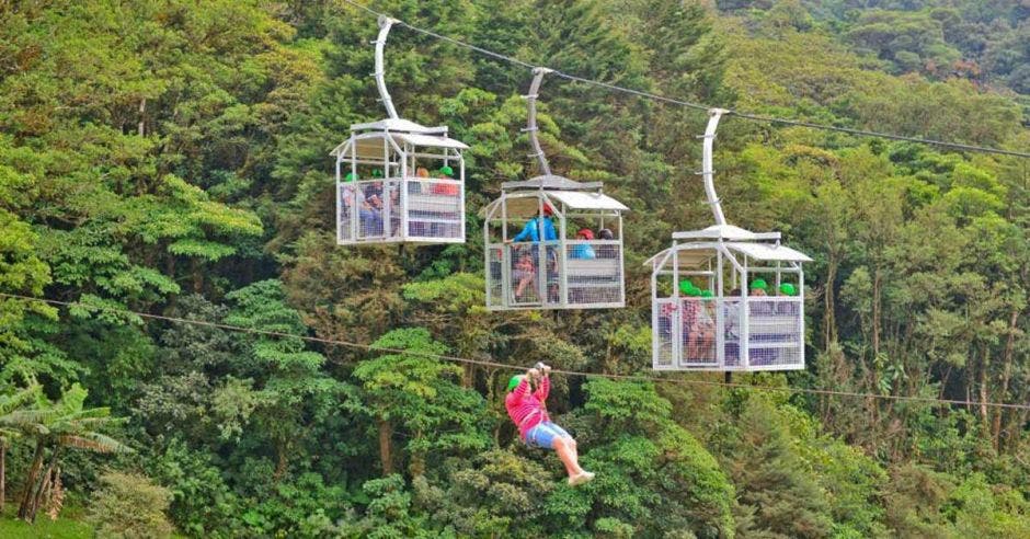 un grupo de turistas sube en teleférico por el bosque tropical