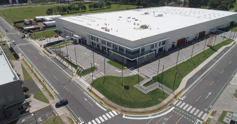 un edificio gris de grandes dimensiones con un amplio parqueo y zona verde