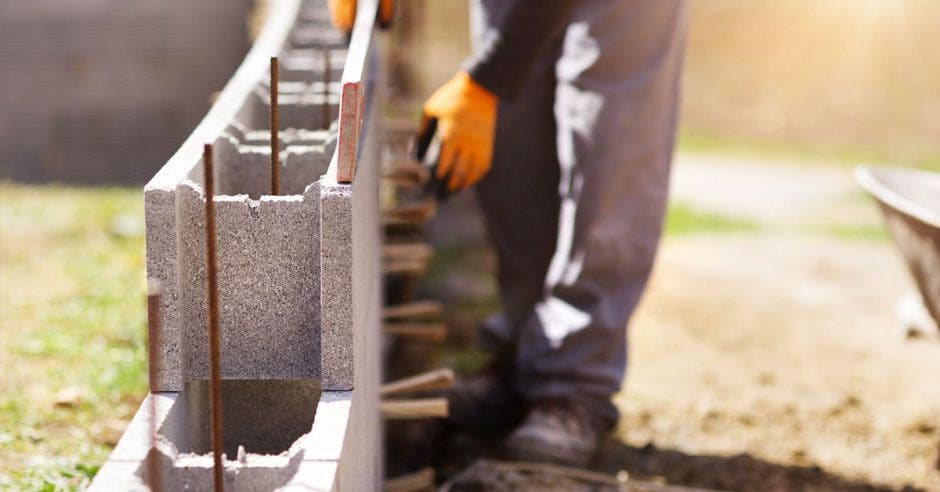 un hombre pone bloques de construcción en medio de varillas de acero