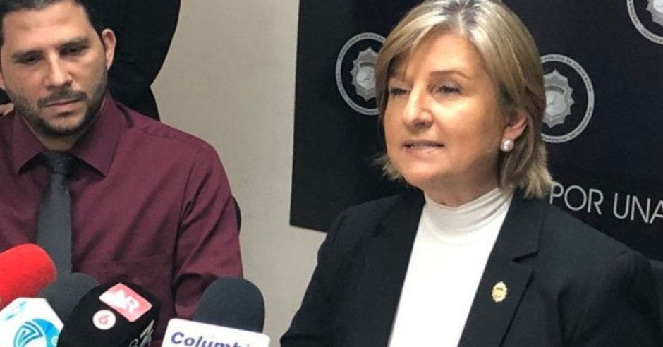 una mujer de pelo corto, saco negro y blusa blanca