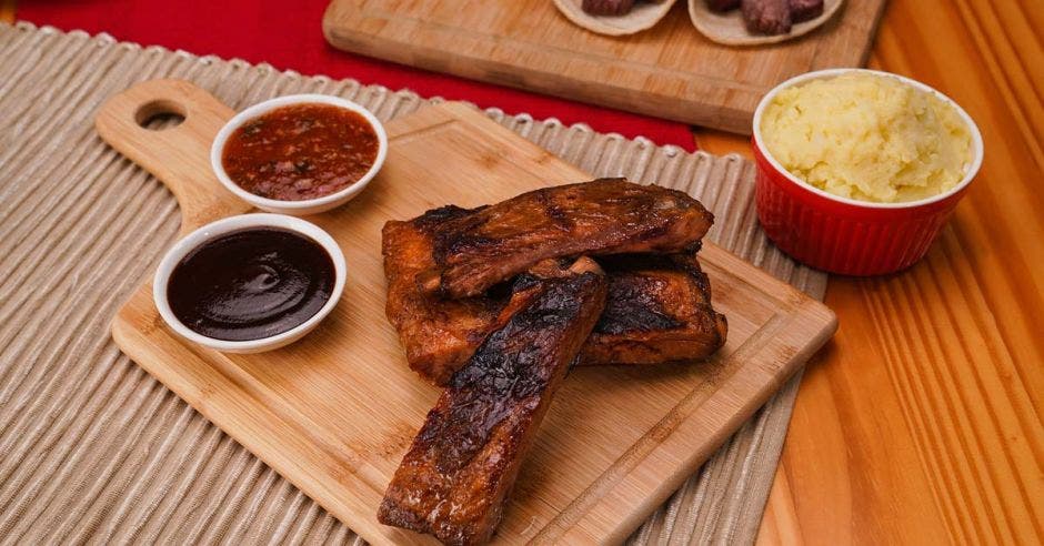 dos costillas cocinadas junto a salsas para acompañar