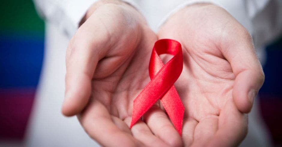 manos con lazo rojo en representación del VIH