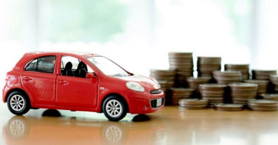 figura pequeña de carro rojo junto a monedas