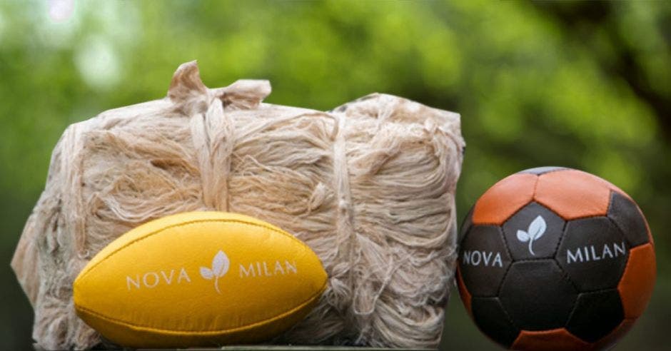 un balón de fútbol americano, un bolso tejido y una pelota de voleibol sobre una mesa