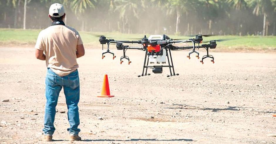 hombre de espaldas volando dron en campo