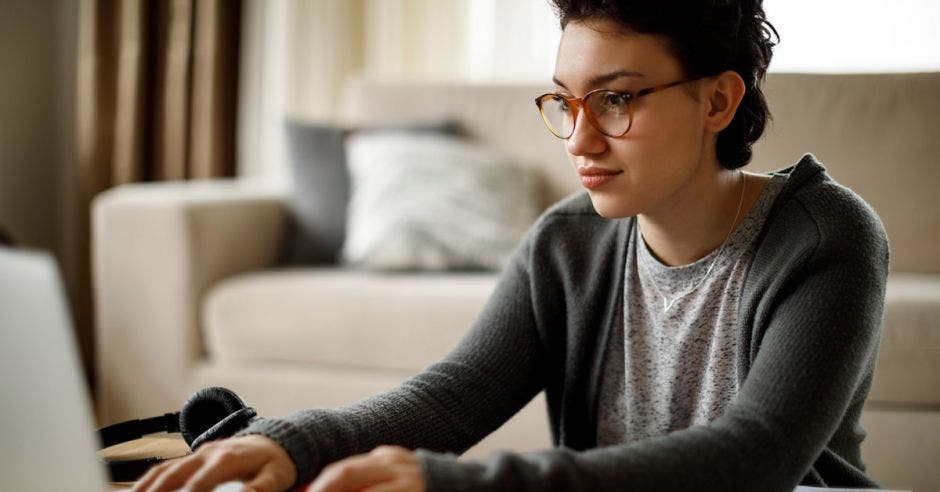 mujer joven con lentes, frente a laptop