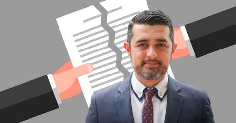 un hombre de barba, saco gris y corbata azul con naranja