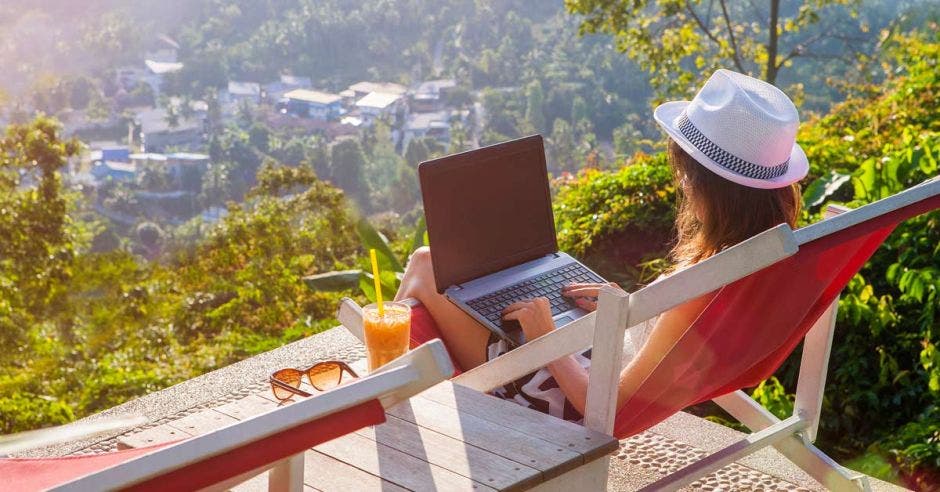 una mujer usa una computadora en un balcón