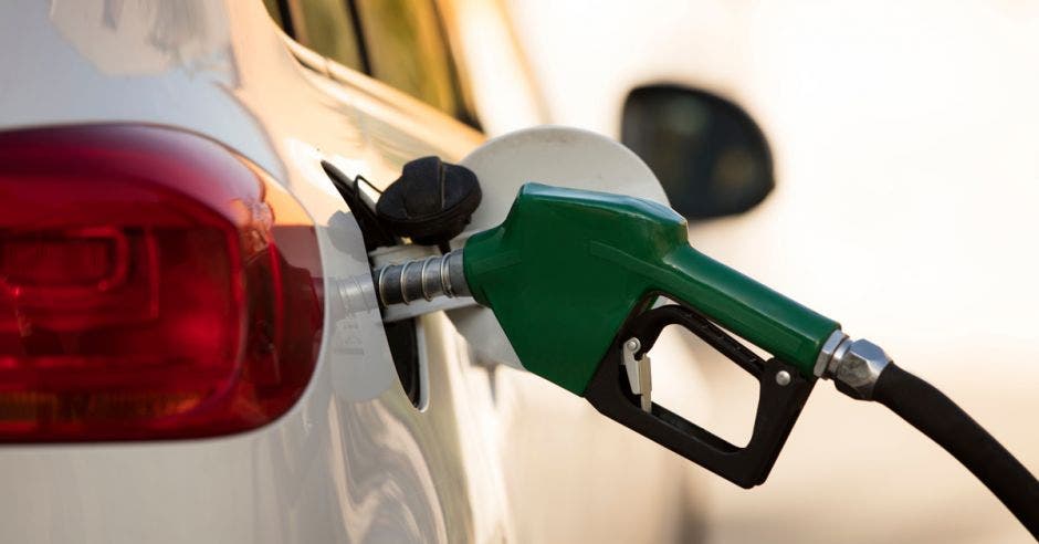 una pistola de gasolina color verde alimentando un carro color blanco