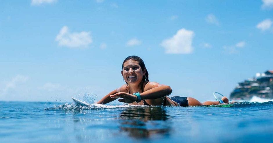 una mujer en vestido de baño sobre una tabla de surf color blanco